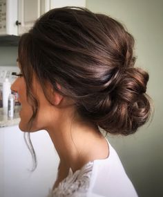 a woman with her hair in a low bun is standing in front of a sink