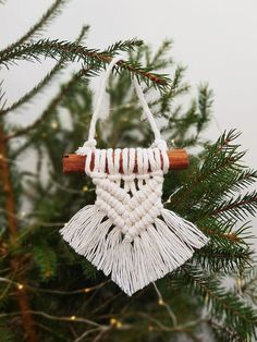 an ornament hanging from a pine tree with white yarn and wooden dows