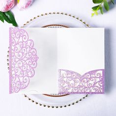 a white and purple wedding card with a bow tie on it next to pink flowers