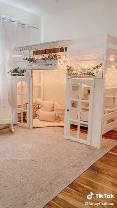 a room with bunk beds and lights on the ceiling is decorated in white, wood flooring