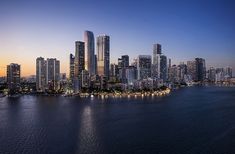 an aerial view of the city skyline at night from across the water with lights on