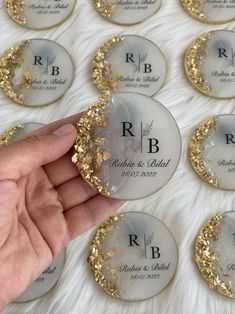 a hand is holding up some wedding coasters with gold flakes on the side