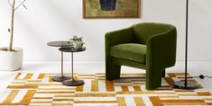 a green chair sitting on top of a rug next to a table with a potted plant