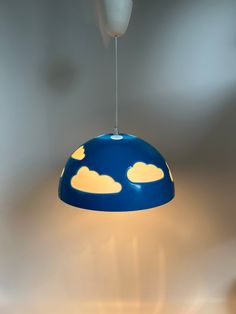 a blue lamp with clouds on it hanging from a ceiling in a living room or bedroom