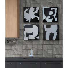 three black and white paintings hanging on the wall next to a sink in a kitchen