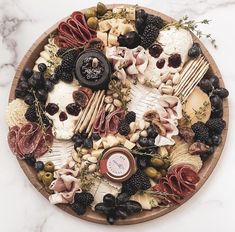 a platter with meats, cheeses, and olives on the side