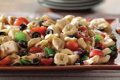 a pasta salad with olives, tomatoes, peppers and other vegetables on a plate