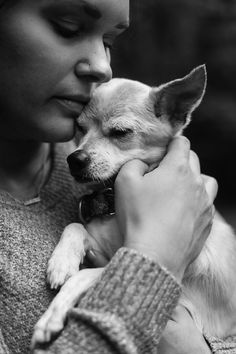 a woman holding a small white dog in her arms and kissing it's face