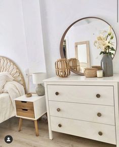 a bedroom with a bed, dresser and large round mirror on it's wall