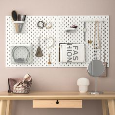 a wooden desk topped with a mirror next to a wall covered in jewelry and accessories