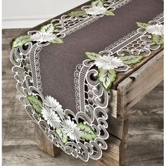 the table runner is decorated with flowers and leaves on brown fabric, along with green trimmings