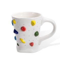 a white coffee cup with multicolored candies on the outside and inside it