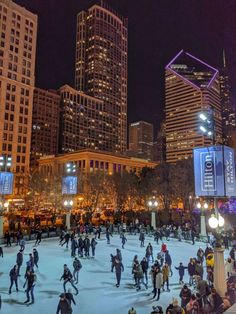 people skating on an ice rink in the city at night