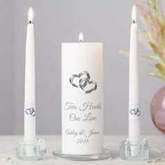 three white candles with two hearts on them