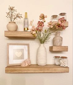 two wooden shelves with vases and other items on them, one shelf holding flowers