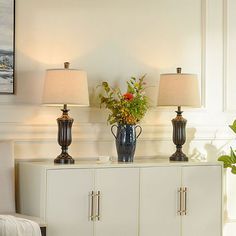 two lamps are sitting on top of a cabinet in a room with white walls and flooring