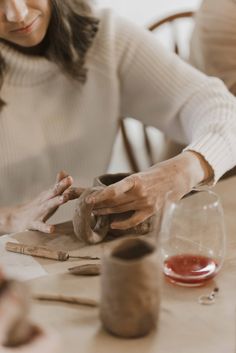 a woman sitting at a table working with clay