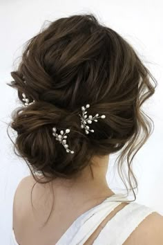 a woman with her hair in a messy updo and two small white flowers on it