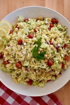 a white bowl filled with pasta salad on top of a red and white checkered table cloth