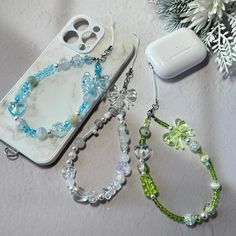 two cell phones are sitting next to each other on a table with beads and charms