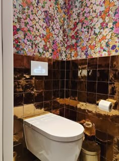 a white toilet sitting in a bathroom next to a wall covered in colorful tile tiles