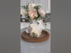 a vase filled with flowers sitting on top of a wooden tray in front of a white cabinet