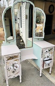 an antique vanity with two drawers and a mirror on the top, in front of a house