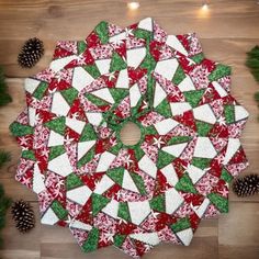 a christmas tree skirt made out of red, green and white fabric with pine cones in the background