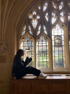 a person sitting on a bench in front of a window