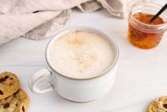 there is a cup of coffee and cookies on the table next to eachother