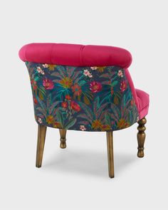 an upholstered chair with pink cushion and floral print on the armrests