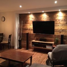 a living room filled with furniture and a flat screen tv mounted on a wall above a wooden table