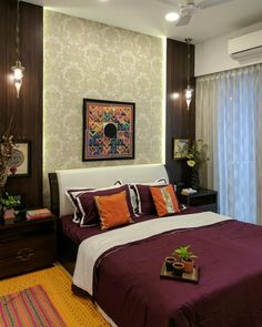 a bedroom with a bed, nightstands and pictures on the wall above it is decorated in shades of purple and orange