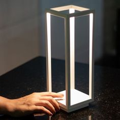 a person's hand on top of a table next to a lit up light