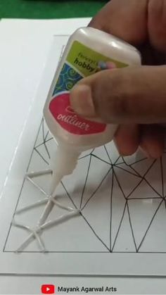 someone is using glue to create a geometric pattern on the paper and then put it in a bottle