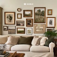 a living room filled with lots of framed pictures on the wall above a white couch