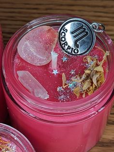 a pink candle with ice and stars in it sitting on a table next to other candles