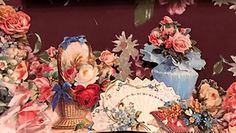 there are many flowers in the vases on this table cloth covered table with other items