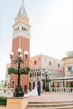 a bride and groom standing in front of a clock tower at disney's grand florie