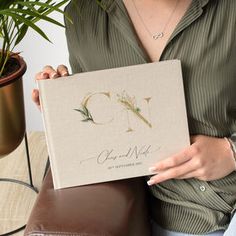 a woman holding up a book with the letter q on it's front cover