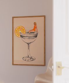 an orange slice sitting on top of a martini glass in front of a framed painting