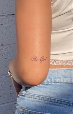 a woman with a small tattoo on her arm that says, stay god in cursive writing