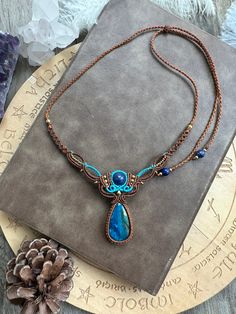 a necklace with a blue stone hanging from it's center on top of a book