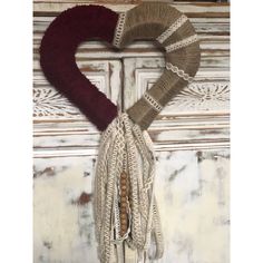 a knitted heart hanging on the side of a door with beads and tassels attached to it