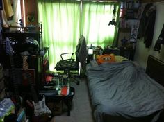 a bedroom with a bed, desk and shelves filled with stuff in it's corner