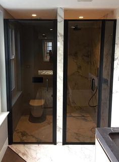 a bathroom with marble floors and black glass doors