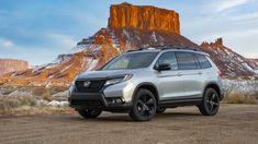 a silver honda passport parked in front of a mountain