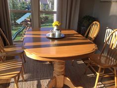 a wooden table with chairs around it and a potted plant on the table top