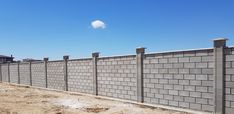 a concrete block wall with cement pillars on the side and blue sky in the background