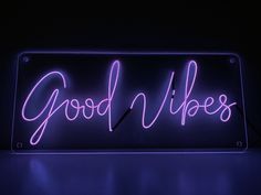 a neon sign with the words good vibes written on it in purple light against a black background